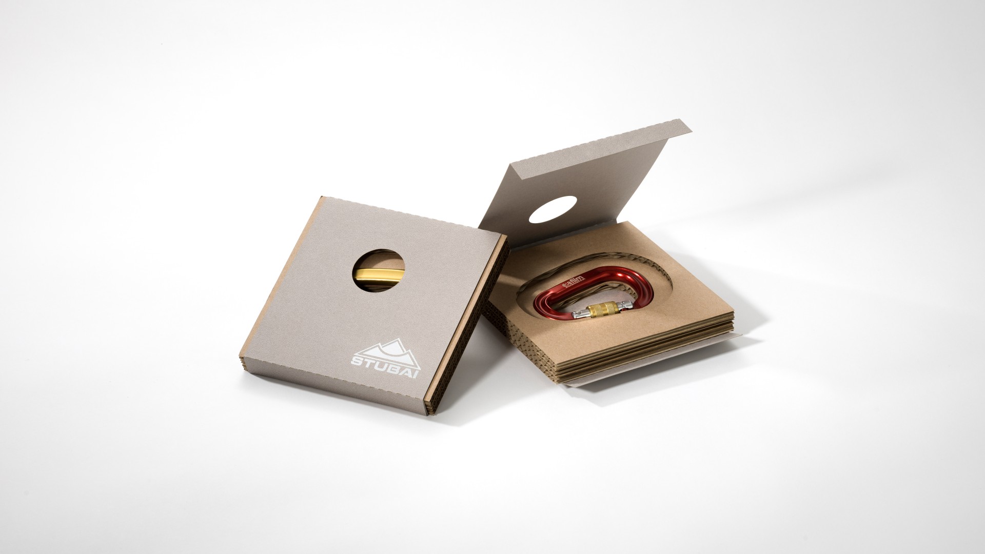Geschlossene und offene Verpackung mit rotem Karabiner im Wellpappe-Schuber liegend