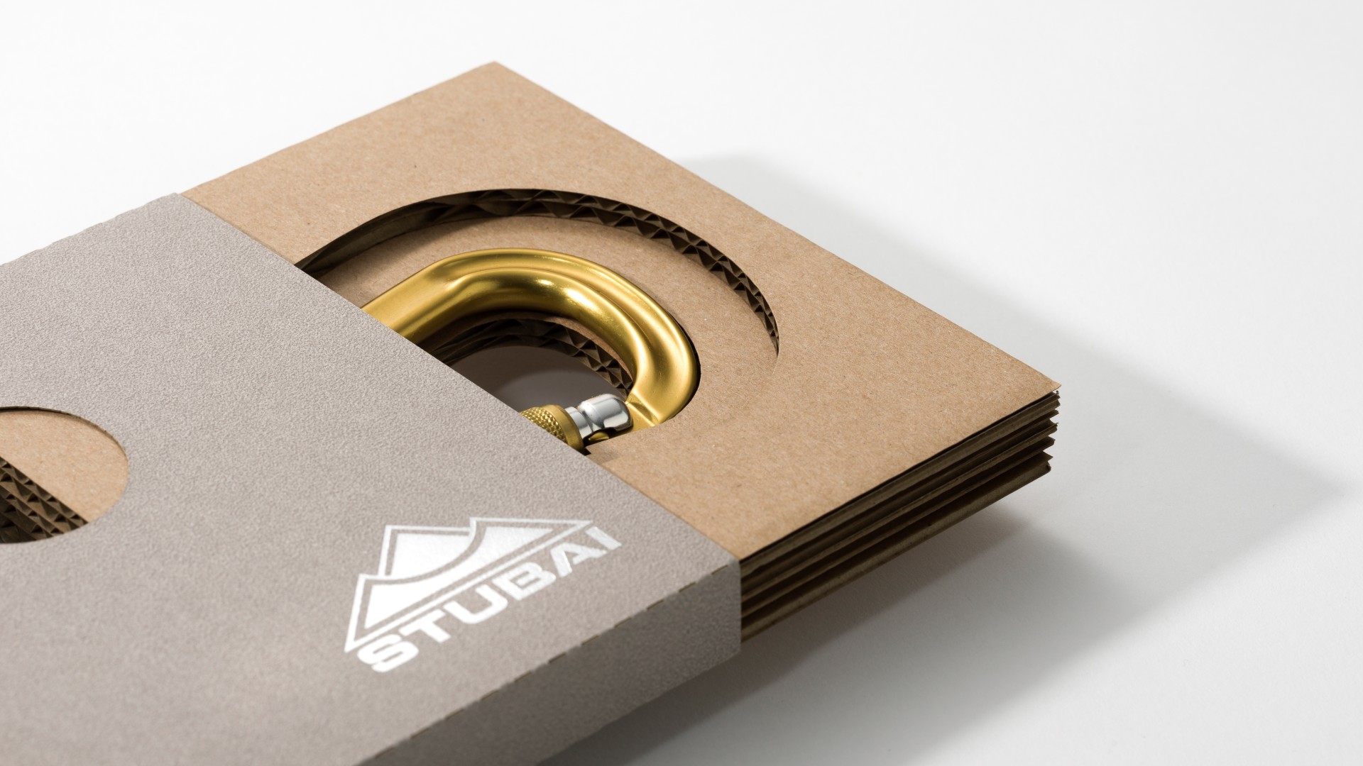 Halboffene Karabinerverpackung mit rotem Karabiner und silbrig geprägtem Logo